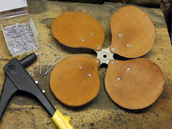 7. Attach the finished blades to the hub using pop rivets and a pop rivet tool. To avoid tearout, the wide flange of the rivet should be against the leather, not the metal of the hub. Be sure opposing blades are weight-matched to within 0.5g before riveting.